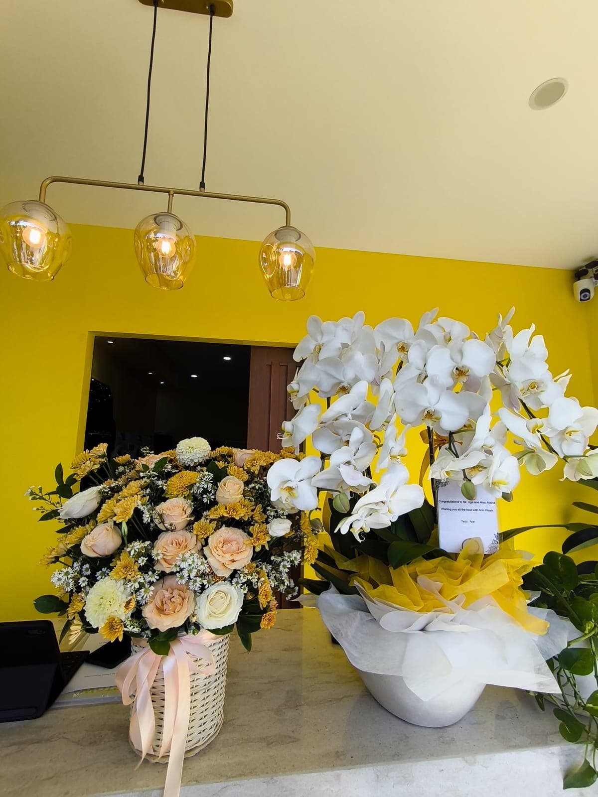 The reception counter with flowers and white orchids beneath brass pendant lights